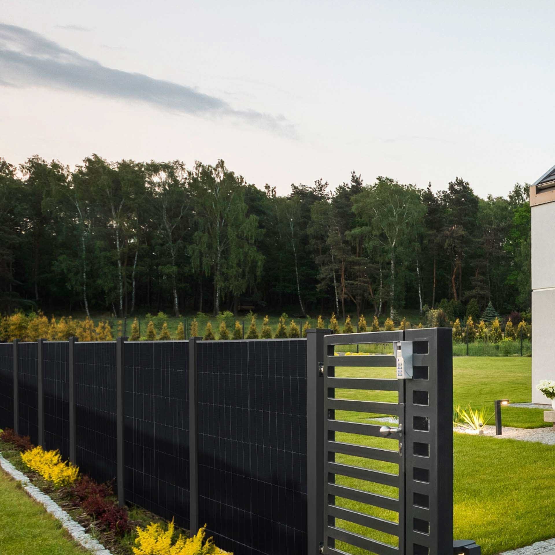 falagotti Solarzaun Puristica am Hausgarten mit flachem PV-Modul vor Bäumen